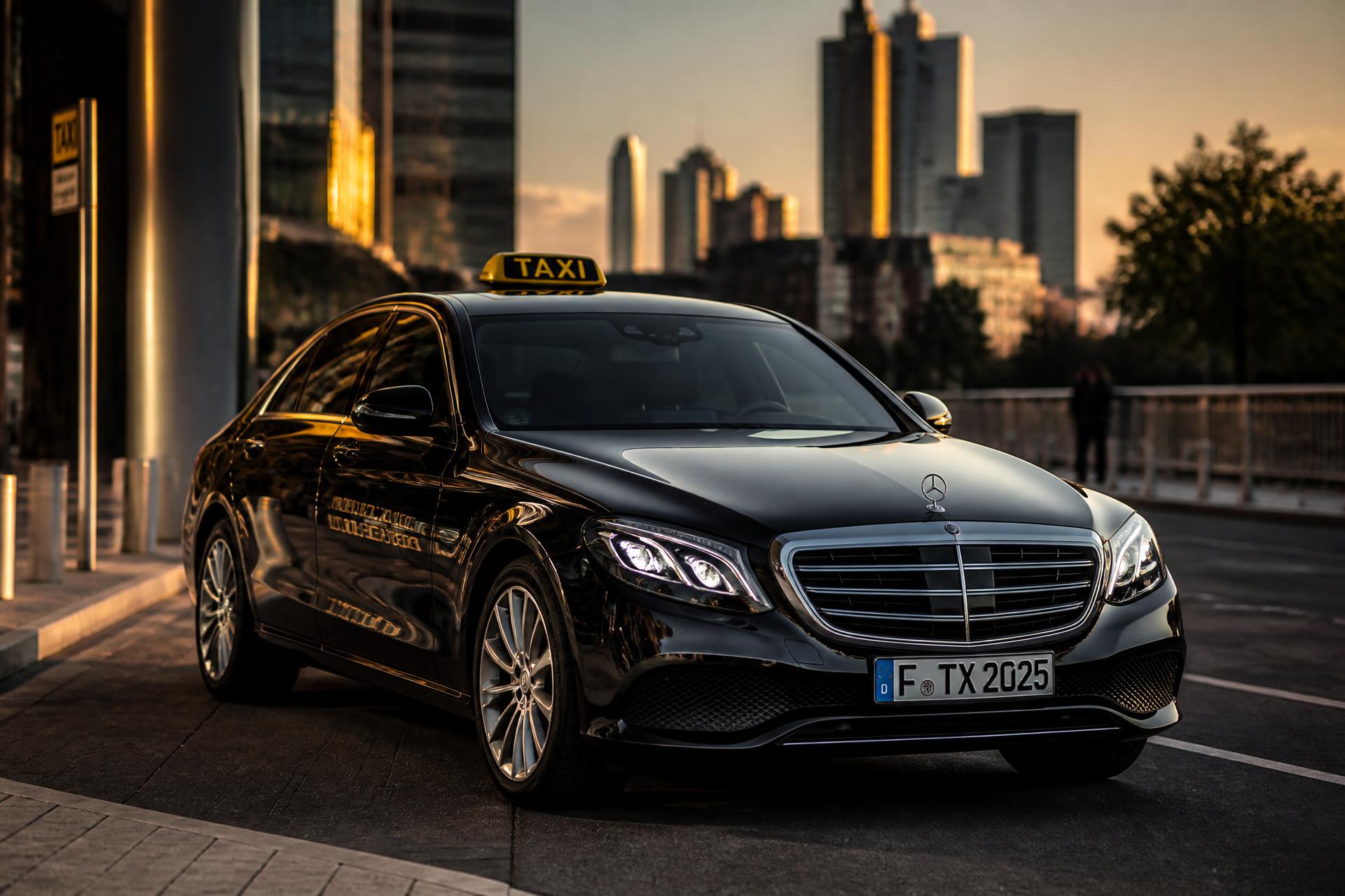 Schwarzes Premium Taxi von LineTaxi in deutscher Großstadt bei Sonnenuntergang